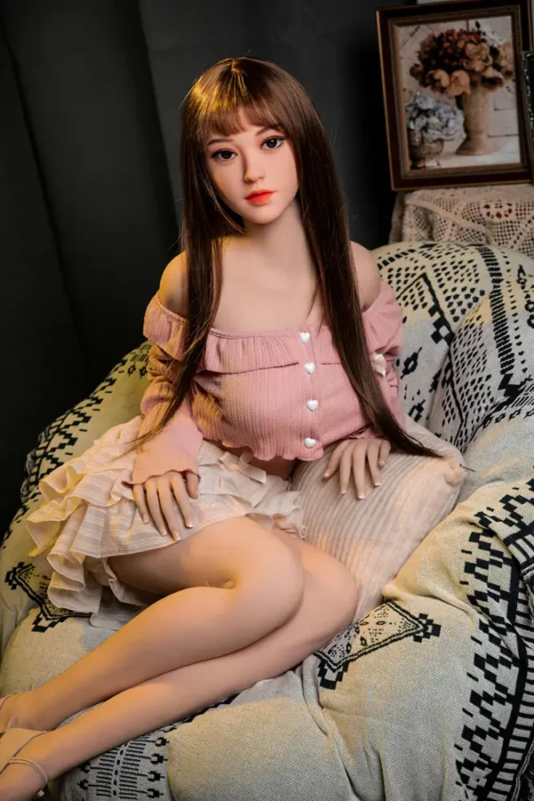 An Asian-faced sex doll with long black straight bangs sat on the couch.