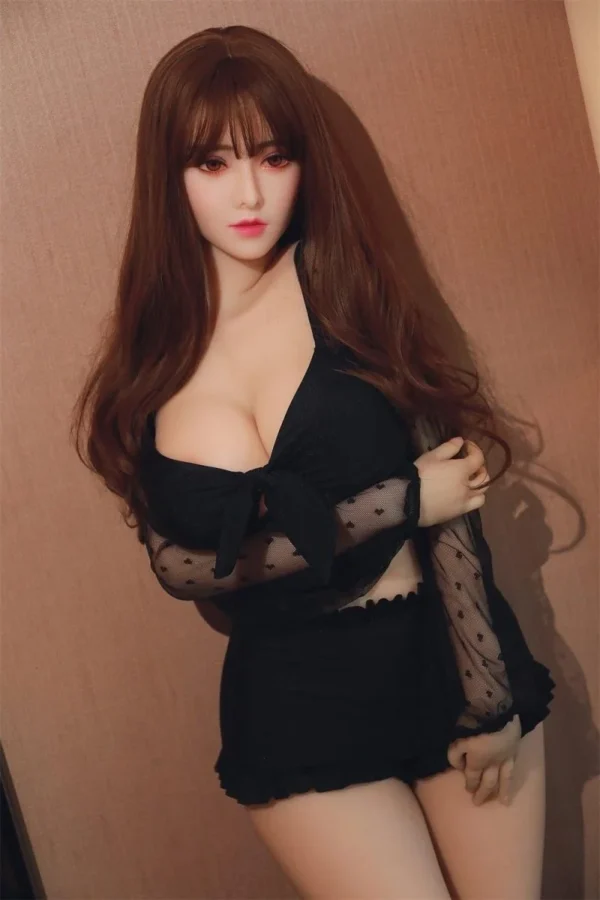 A sweet-looking sex doll with long hair and bangs stand on the ground, her right hand touching her left elbow.