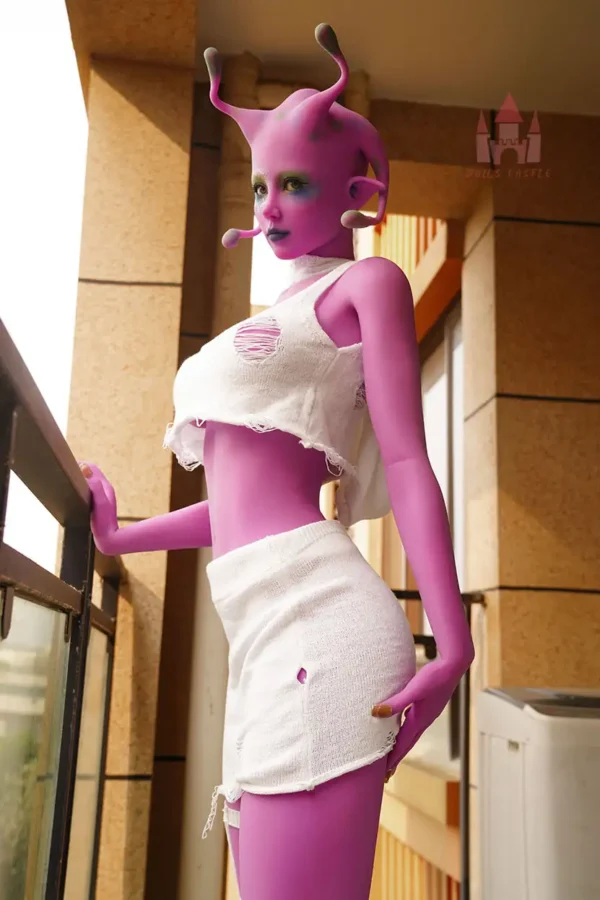 A purple alien e-cup life size love doll stands on the ground, wearing a white set.