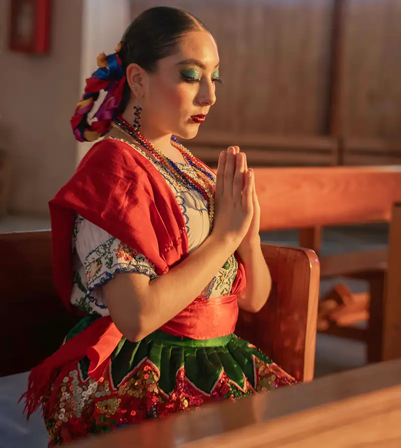 A Latina woman, dressed in national dress, attends a church service.